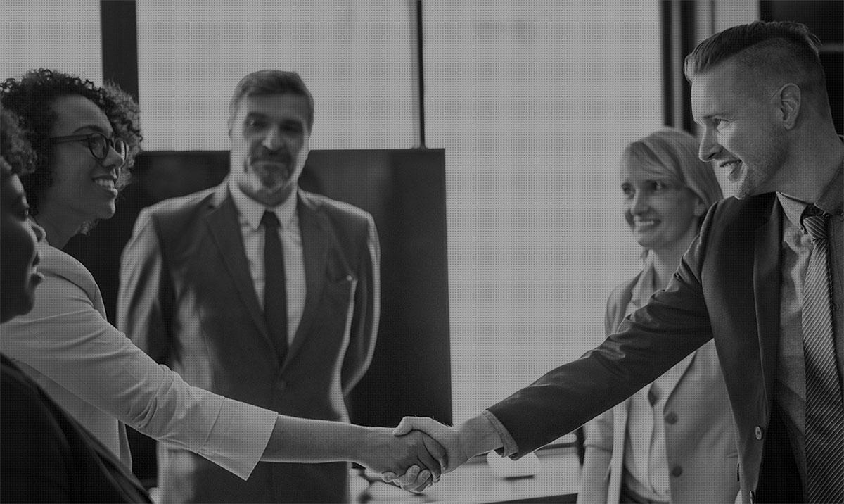 Professionals exchange a handshake over a conference table