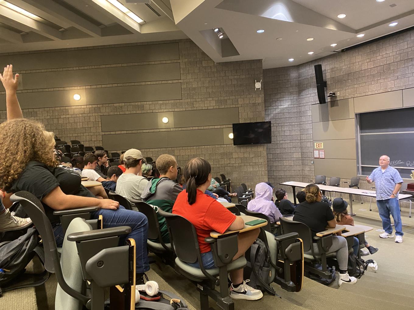 Students listen to lecturer Sam Nelson, while one student raises their hand