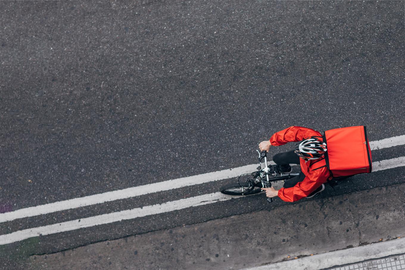 Delivery worker cycling along a paved road