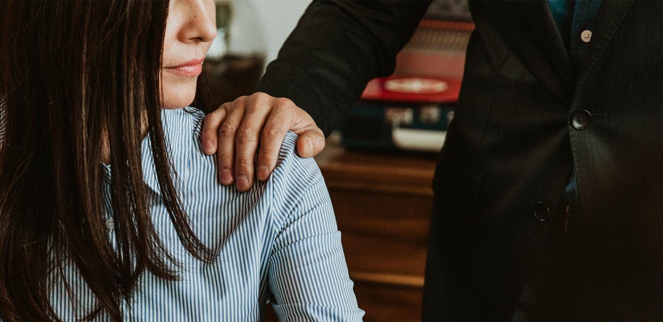 A woman turned to the side looking at a man's hand on her shoulder