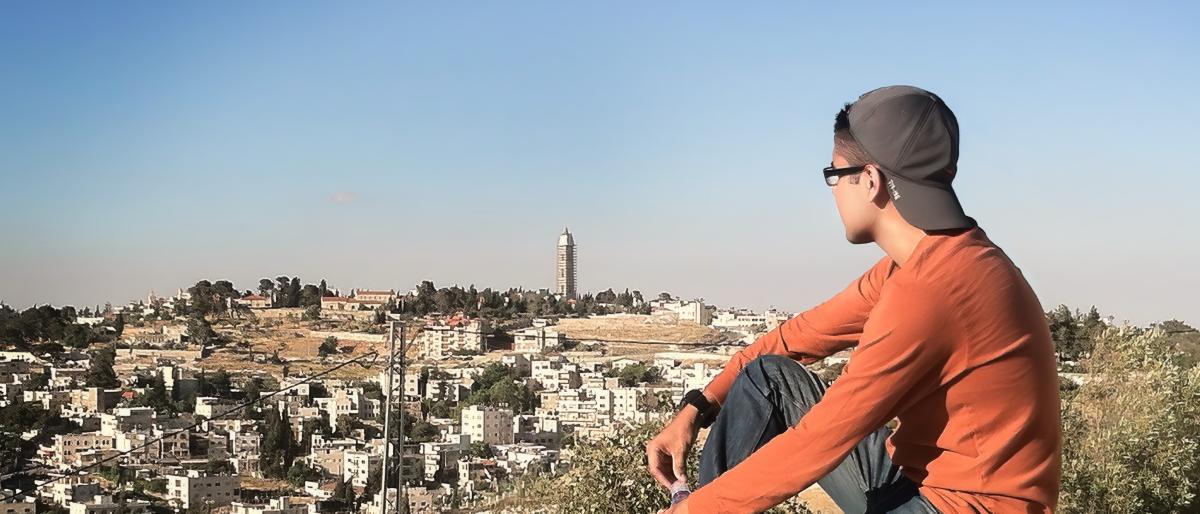 Person sitting on a wall overlooking a city