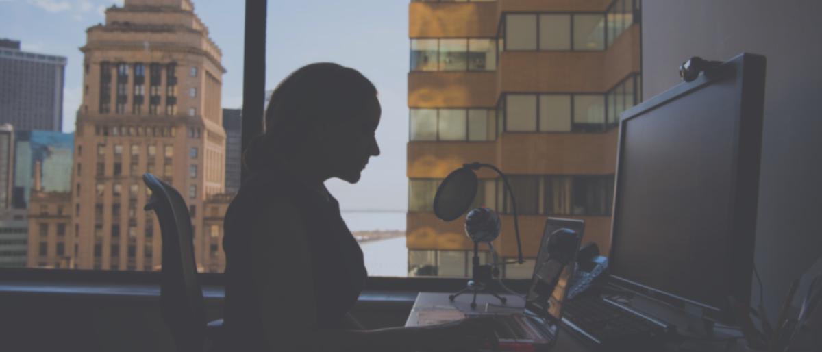 Silhouetted woman working at a desk on a computer