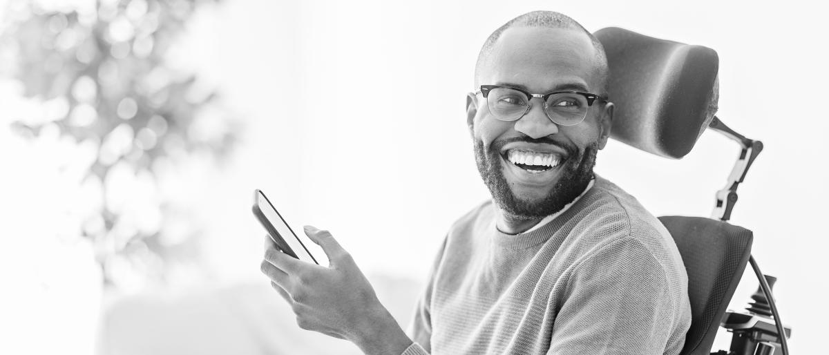 Wheelchair user smiling holding a cellphone