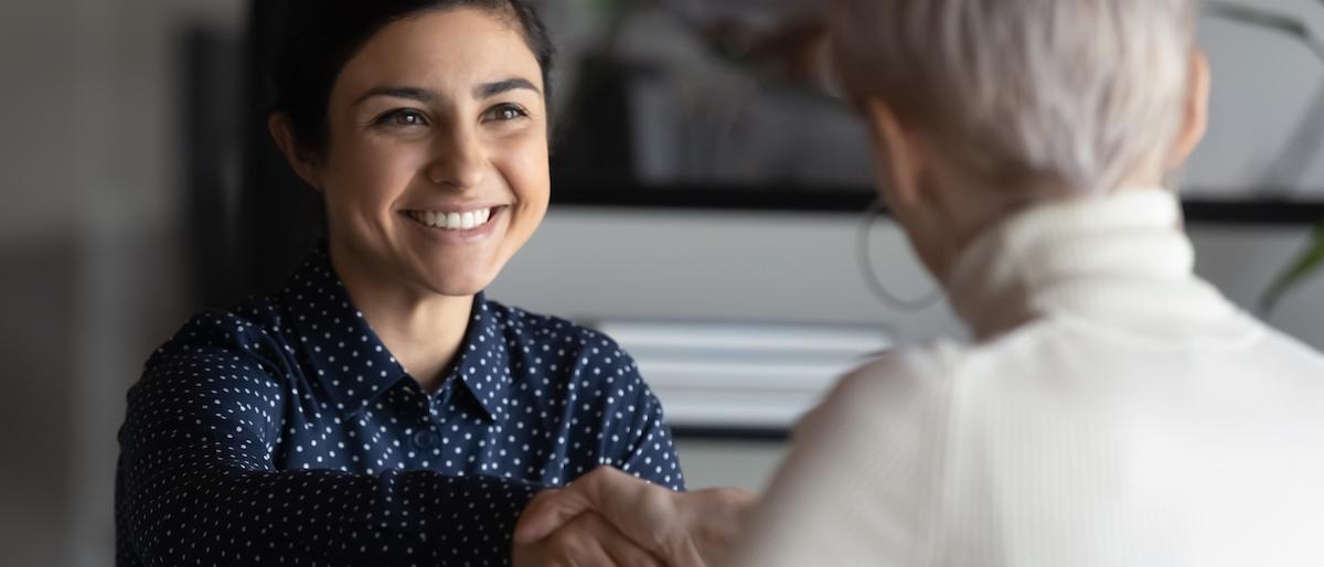 Two people shake hands during a job interview
