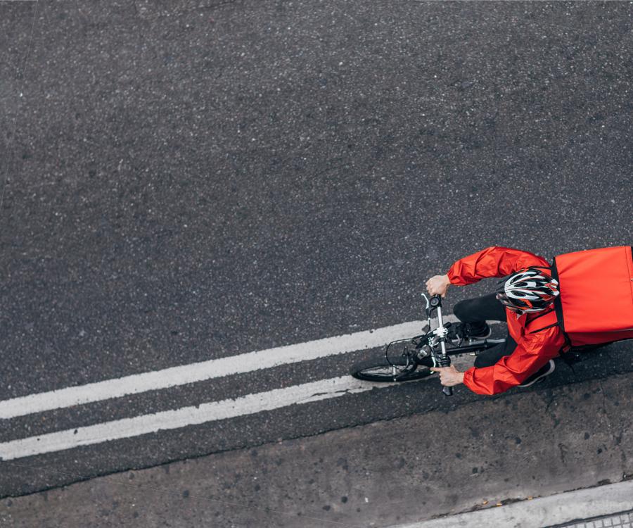 Delivery worker cycling along a paved road