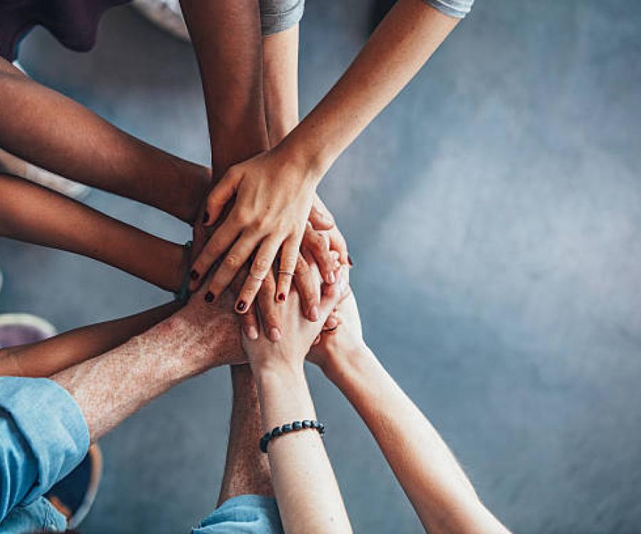 multiple hands of diverse skin tones meeting in the center