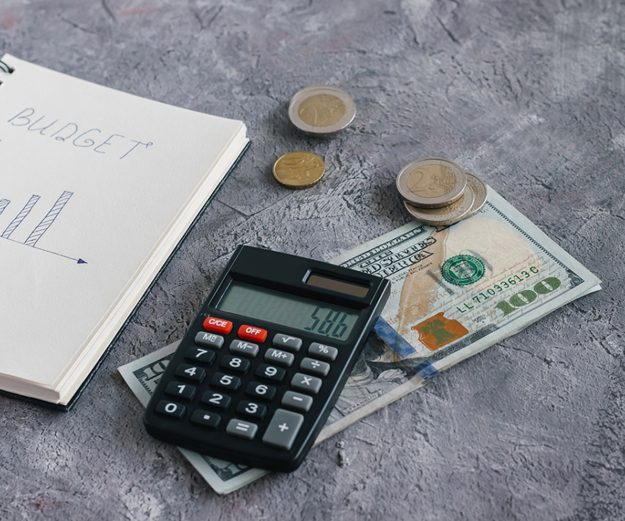 A calculator, cash and budget journal on a table. 