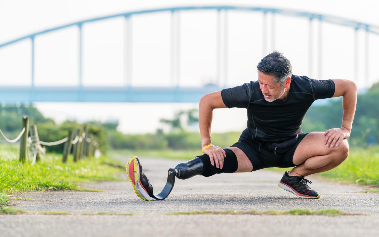 athlete with a prosthetic leg stretching outside