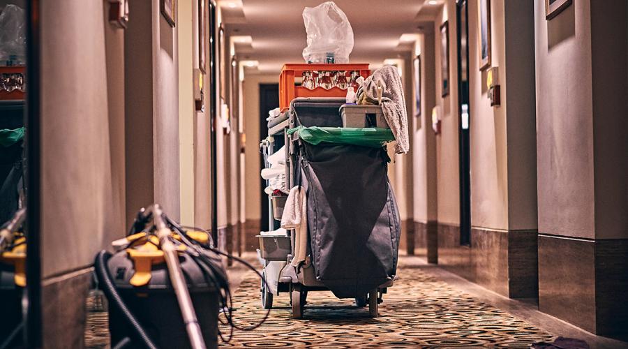 Housekeeping cart with cleaning supplies in a hotel hallway.