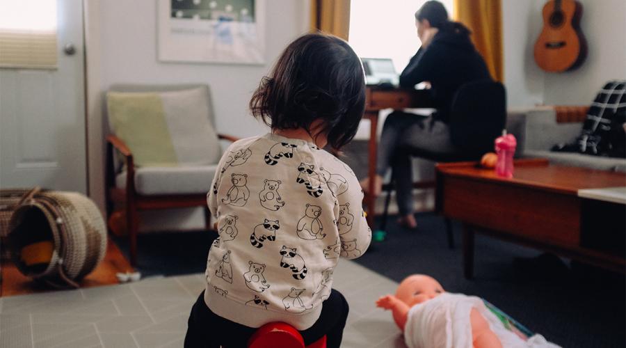 children playing at home with a woman working in the background