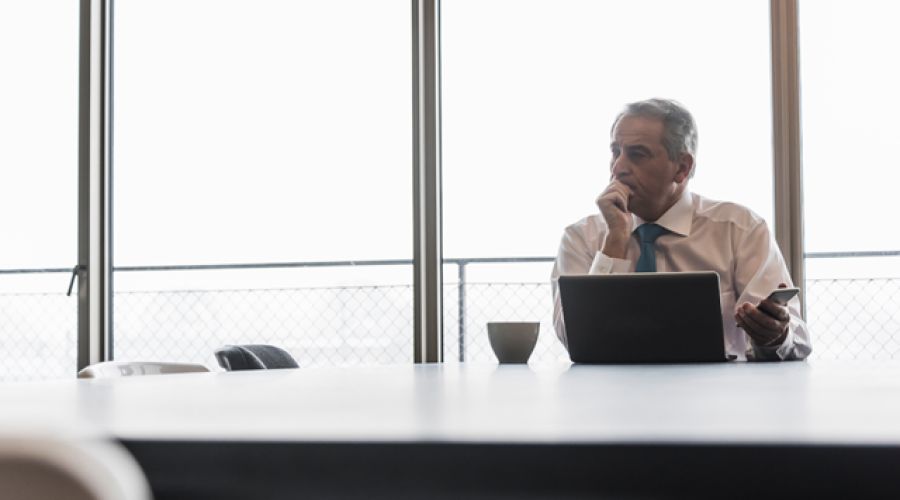 A man sits in thought at a conference table 