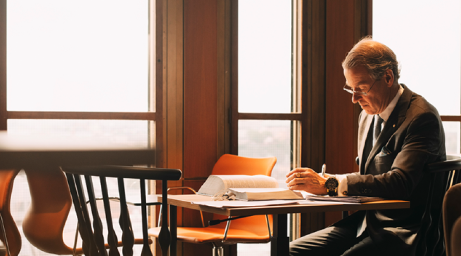 A man sits reading at a desk