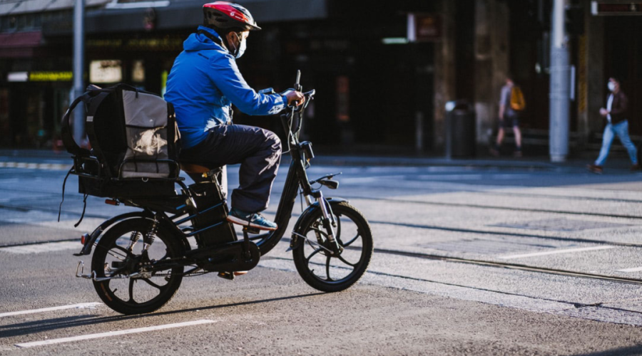 Man wearing a face mask riding an e-scooter on a city street