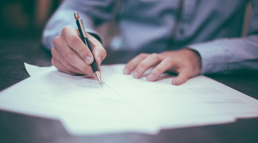  a person's hand writing on papers