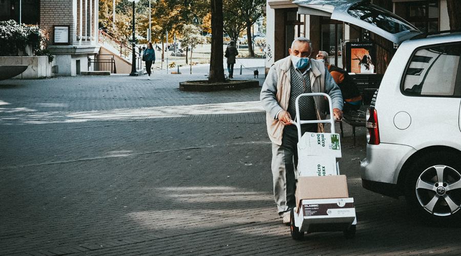 a person wearing a mask moving boxes on a handtruck to illustrate reopening and ppe