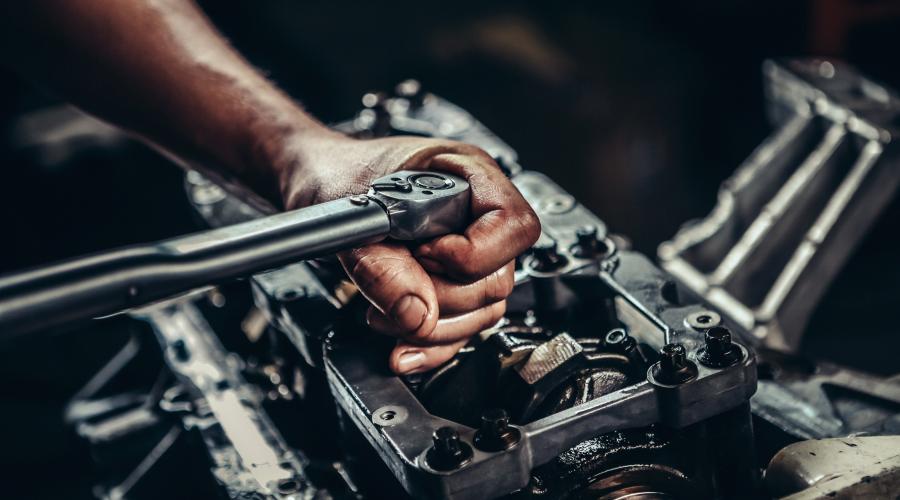 Mechanic uses hand tool to work on car engine