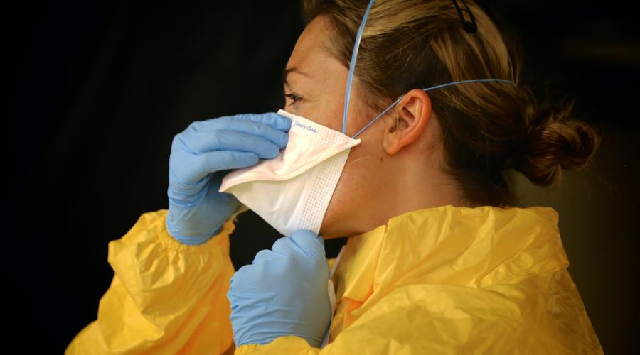 woman wearing ppe putting on mask