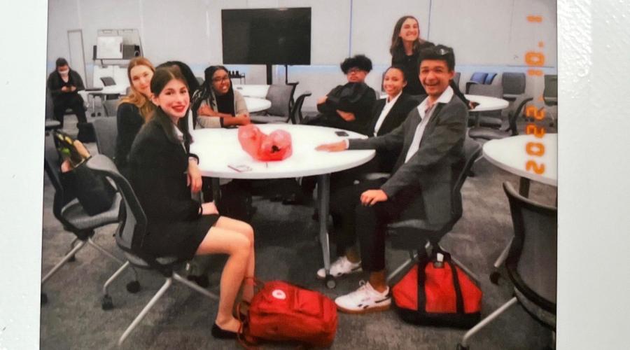 Students in suits sit around a table