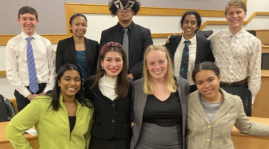 students pose in two rows wearing suits after a tournament