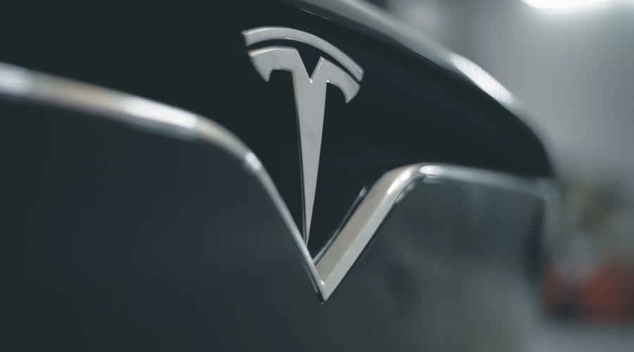 Close up of Tesla logo on front grill of gray Tesla car