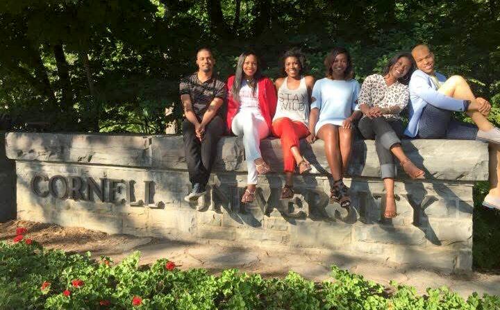 Melanie Stewart ’10 with friends sitting on a concrete wall that says Cornell University