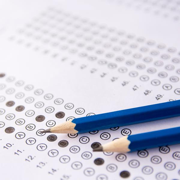 two blue pencils on top of a test to be graded through a scanner