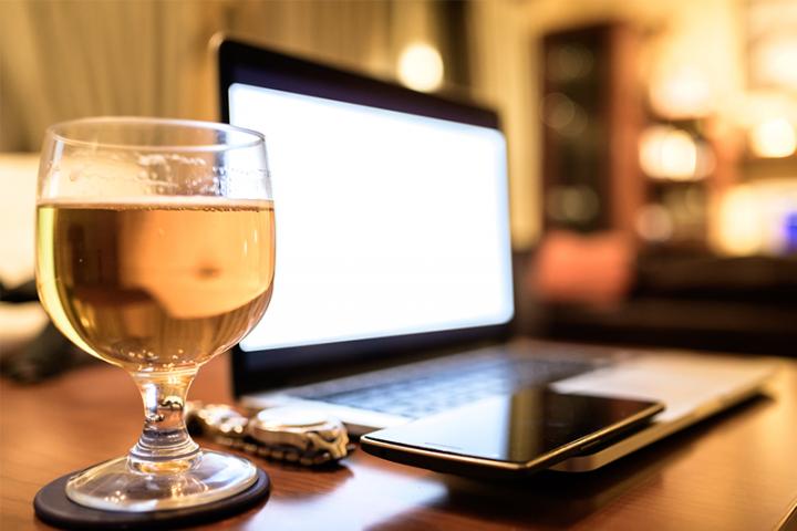 Beer glass next to wristwatch, smart phone and laptop