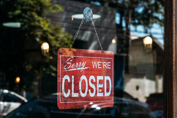 "Sorry, we're closed" sign hanging on a business door.
