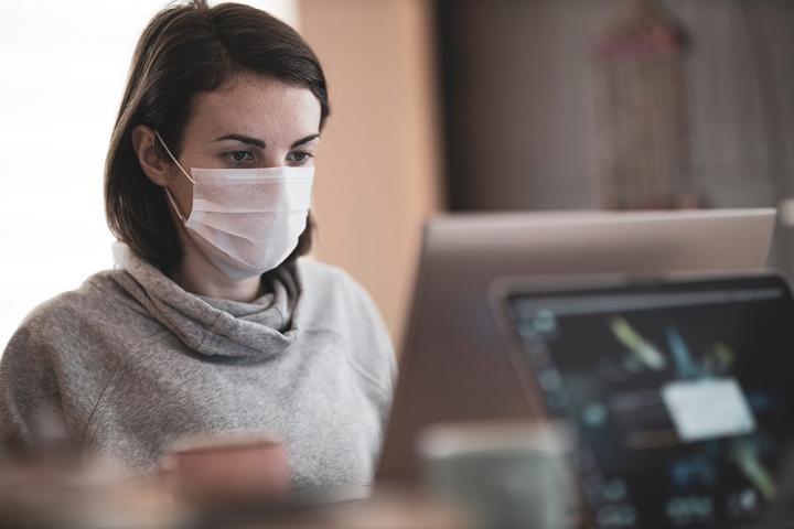 someone wearing a mask while working at a computer monitor