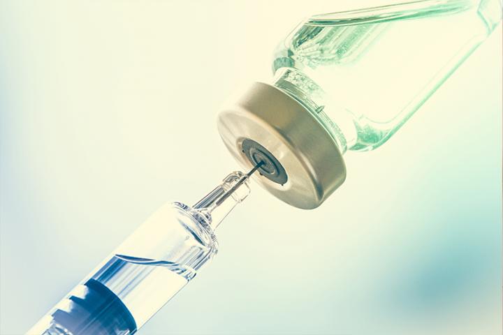 Close-up view of a needle inserted into a vaccine vial