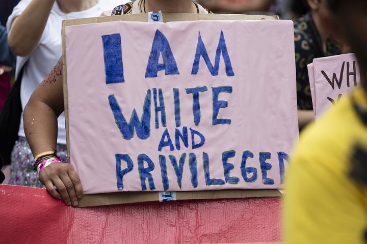 A sign stating, "I am white & privileged"