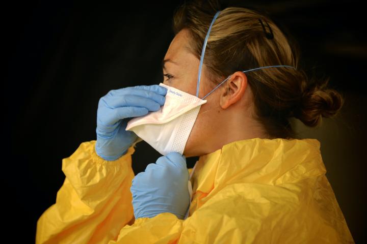 woman wearing ppe putting on mask