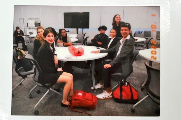 Students in suits sit around a table