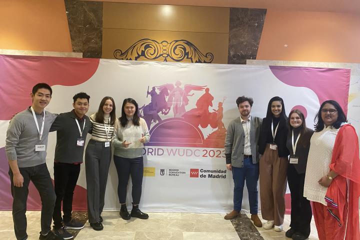 8 Cornellians stand in front of the USUDC Madrid logo