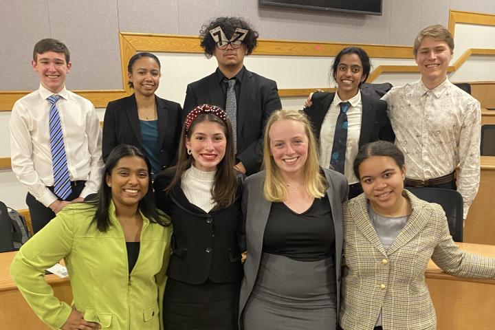 students pose in two rows wearing suits after a tournament