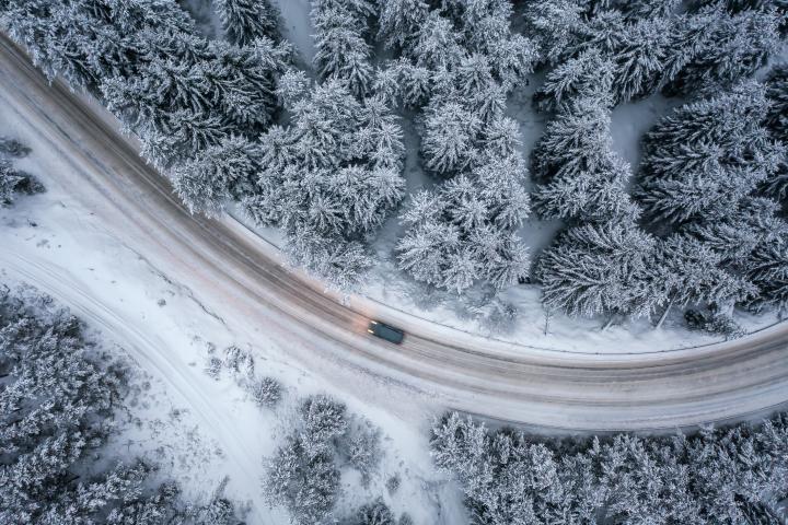 A lone car travels a snow-covered rural road
