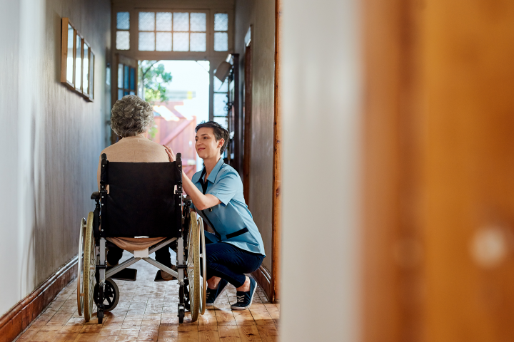 A nurse tends to a wheelchair bound patient in her home