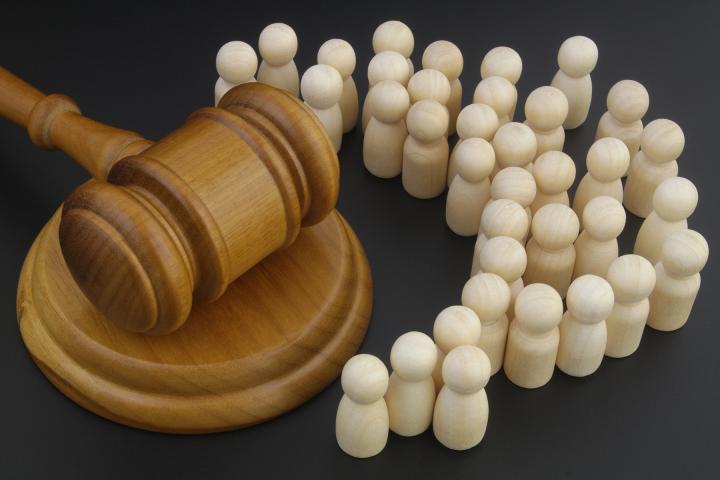 A gavel surrounded by small white wooden figures
