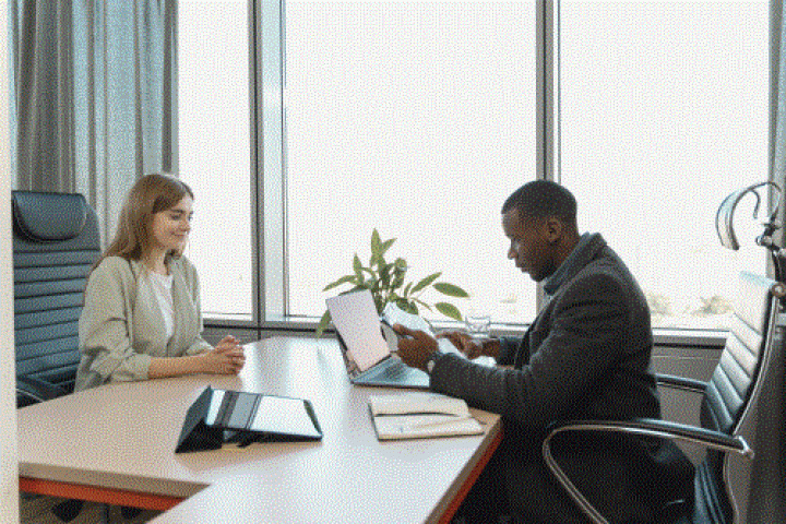 two people talking on either side of a desk