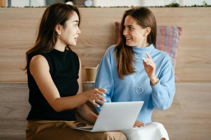 two women talking while sitting with a laptop in front of them