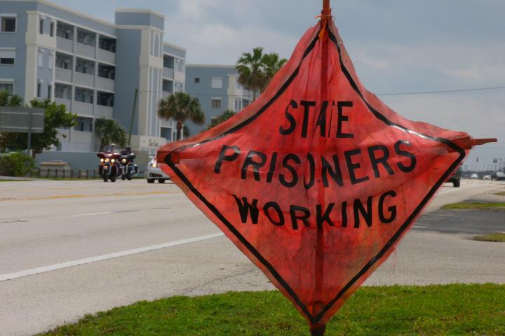 Sign by a road that says "State Prisoners Working"