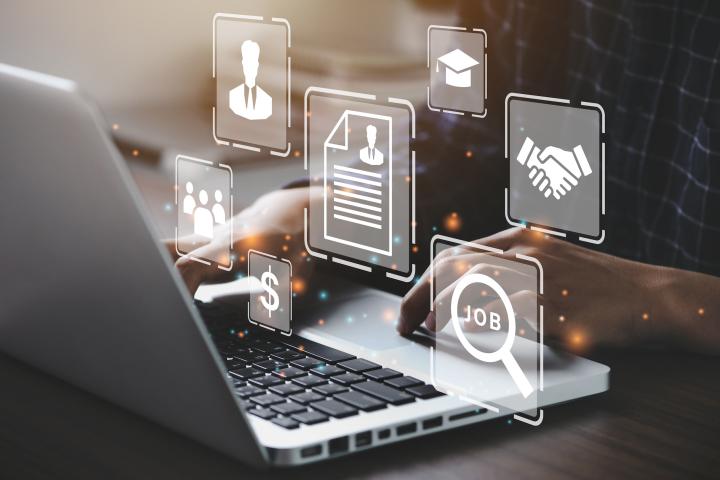 Visualization of business activities as icons floating around a person working on a laptop .