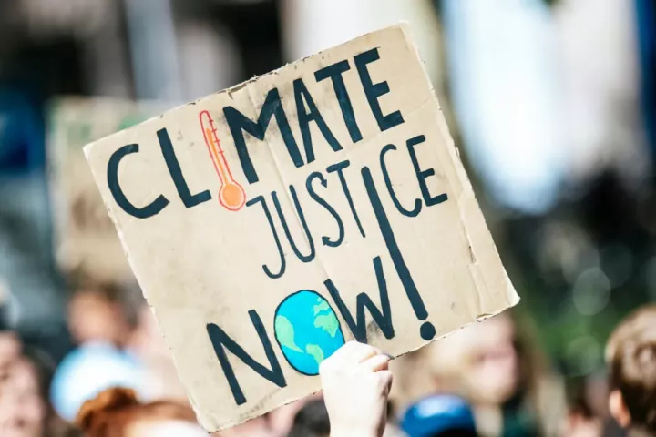 A sign at a demonstration that says "climate justice now!"