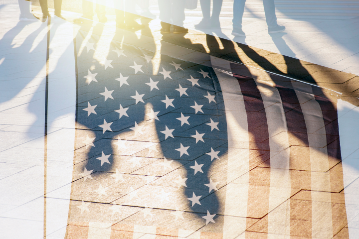 A shadow of people overlays an American flag