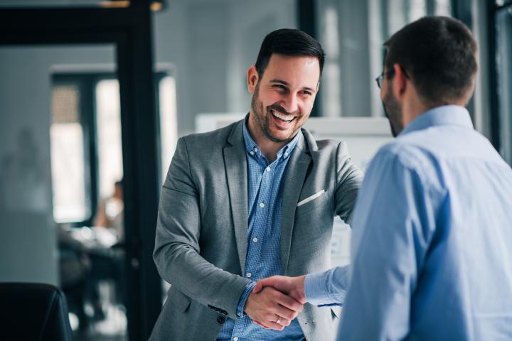 A man smiles broadly while shaking hands 