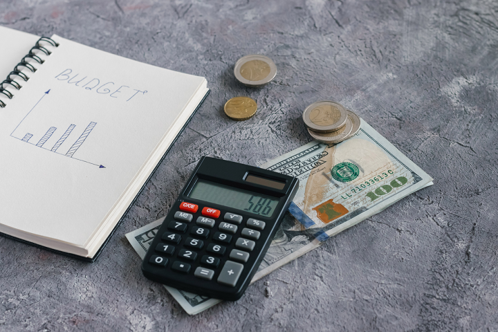 A calculator, cash and budget journal on a table. 