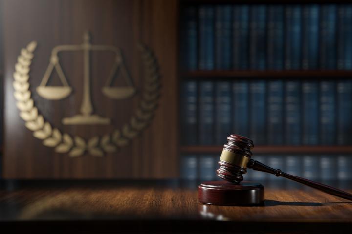 Image of law library with scales of justice emblem and a gavel in the foreground