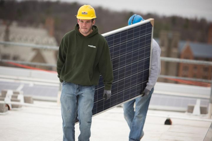 Workers carrying a solar panel 