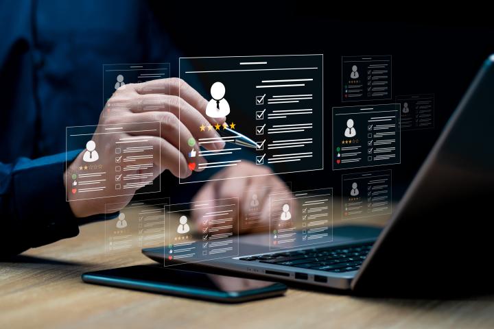 Image of hands with a pen selecting something on a transparent screen with a person profile on it