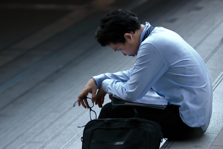 A worker sits with his head down